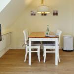 Dining area with table, chairs, and TV on the wall.