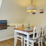 Dining area with table, chairs, and TV mounted on the wall.