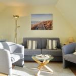 Living room with sofa, two armchairs, and glass table under sloped ceiling.