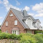 House with brick facade and balcony under blue sky