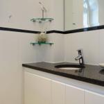 Bathroom with sink, mirror, and glass shelf with bird decoration.