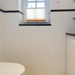 Bathroom with toilet, sink, and window with blinds.