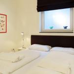 Bedroom with bed, nightstand, and window with artwork on the wall.