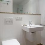 Bathroom with sink, mirror, and toilet. Modern fixtures and light-colored walls.