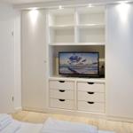 Bedroom with white closet, TV, and wooden floor.