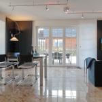 Modern furnished living area with dining table, sofa, and glass doors to the terrace.