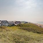 House on dunes with view of beach and sea.