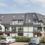 Modern multi-family house with balconies and skylights. Parking spaces in front of the building.