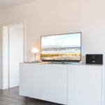 TV on white cabinet, lamp and speaker beside it