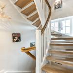Wooden spiral staircase with white pillars and wall posters