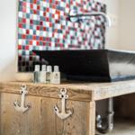 Sink on rustic wooden cabinet with anchors and mosaic wall