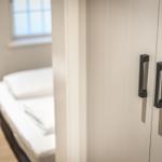 Bedroom with white wardrobe and bed. Window and picture on the wall.