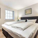 Bedroom with double bed, window, nightstands, and wall art.