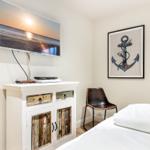Bedroom with bed, TV, and wall art featuring an anchor