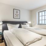 Room with double bed, window, and bedside table with lamp.