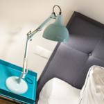 Bedroom with gray headboard, white bedding, and blue bedside lamp.