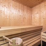 Sauna with wooden walls, bench, and wooden bucket.