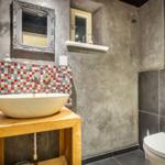 Bathroom with sink on wooden stand, mosaic wall, and toilet.