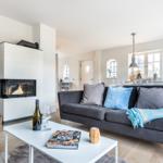 Living room with sofa, fireplace, and dining table in background.