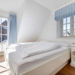 Schlafzimmer mit Doppelbett, Fenster und Holzboden.