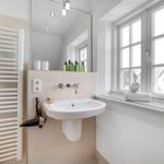Badezimmer mit Waschbecken, Spiegel und Fenster. Handtuch und Duschgel sind vorhanden.