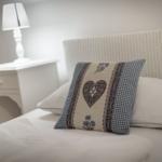 Bettkopfteil aus geflochtenem Material, Kissen mit Herz und Blumenmuster, Nachttisch mit Lampe.