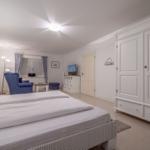Schlafzimmer mit Bett, Kleiderschrank und Sitzgelegenheit.
