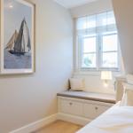 Schlafzimmer mit Fensterbank, Bett und Wandbild mit Segelboot.