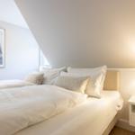 Schlafzimmer mit Bett, Nachttisch und Wandbild mit Segelboot.