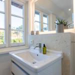 Badezimmer mit Waschbecken, Spiegel und Fenster zur Aussicht.