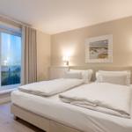 Schlafzimmer mit Blick aufs Meer und weißem Bett.