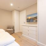 Schlafzimmer mit Bett, Kleiderschrank und Fernseher an der Wand.