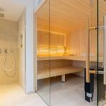 Dusche und Sauna mit Glaswänden und Holzbänken.