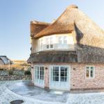 Haus mit Strohdach und Backsteinfassade. Vorderhof mit leichtem Schnee.