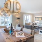 Essbereich mit Holztisch und Sitzgelegenheiten. Im Hintergrund Wohnzimmer mit Sofa und Kamin.