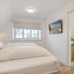 Schlafzimmer mit Doppelbett, Fenster und Bad im Anschluss.