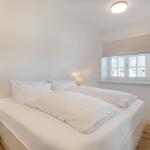 Schlafzimmer mit Doppelbett, Fenster und Nachttisch