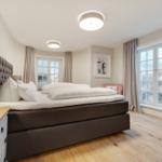 Schlafzimmer mit großem Bett, Holzboden und Fenstern mit Meerblick.