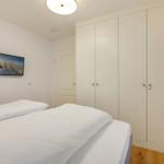 Schlafzimmer mit weißem Bett, Kleiderschrank und Wandbild