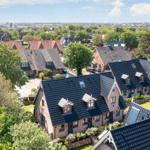 Dorf mit Häusern und Bäumen unter blauem Himmel