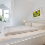 Schlafzimmer mit Doppelbett, Fenster und Kunstwerk an der Wand.