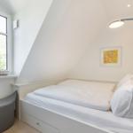 Dachgeschosszimmer mit Bett, Fenster und Wandbild.