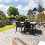 Terrasse mit Tisch, Stühlen und Steinpflaster. Hinterhof mit Holzzaun und Grünflächen.