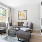 Wohnzimmer mit Sofa, Sessel, Kamin und großem Fenster.