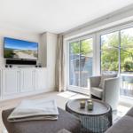 Wohnzimmer mit TV, Sofa und Blick auf Balkon.