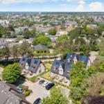 Luftbild von Häusern mit Gärten und Blick auf die Stadt und das Meer.