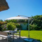 Garden with table, chairs, and umbrella. Lawn and flower beds.