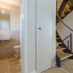 Bathroom with sink and toilet next to a spiral staircase.