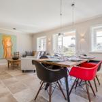 Dining room with table, chairs, and fireplace. Living area with sofa and wall art.