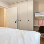 Bedroom with bed, wardrobe, and desk with TV